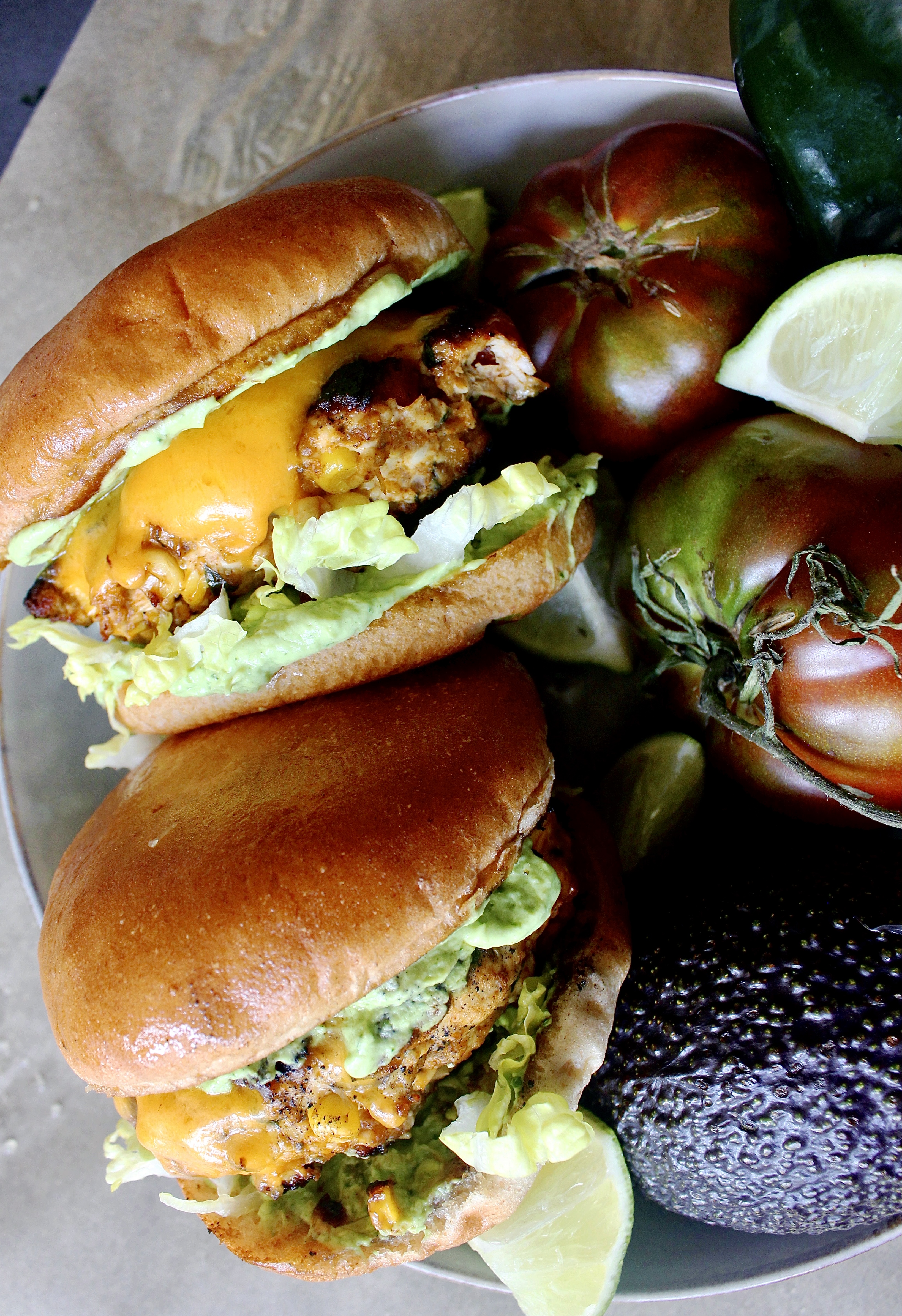 Peppers, corn, and onions sauteed in tons of spices and folded into the juiciest, chicken patties: these Fiesta Corn Cheddar Chicken Burgers with Avocado Sauce are next level amazing.