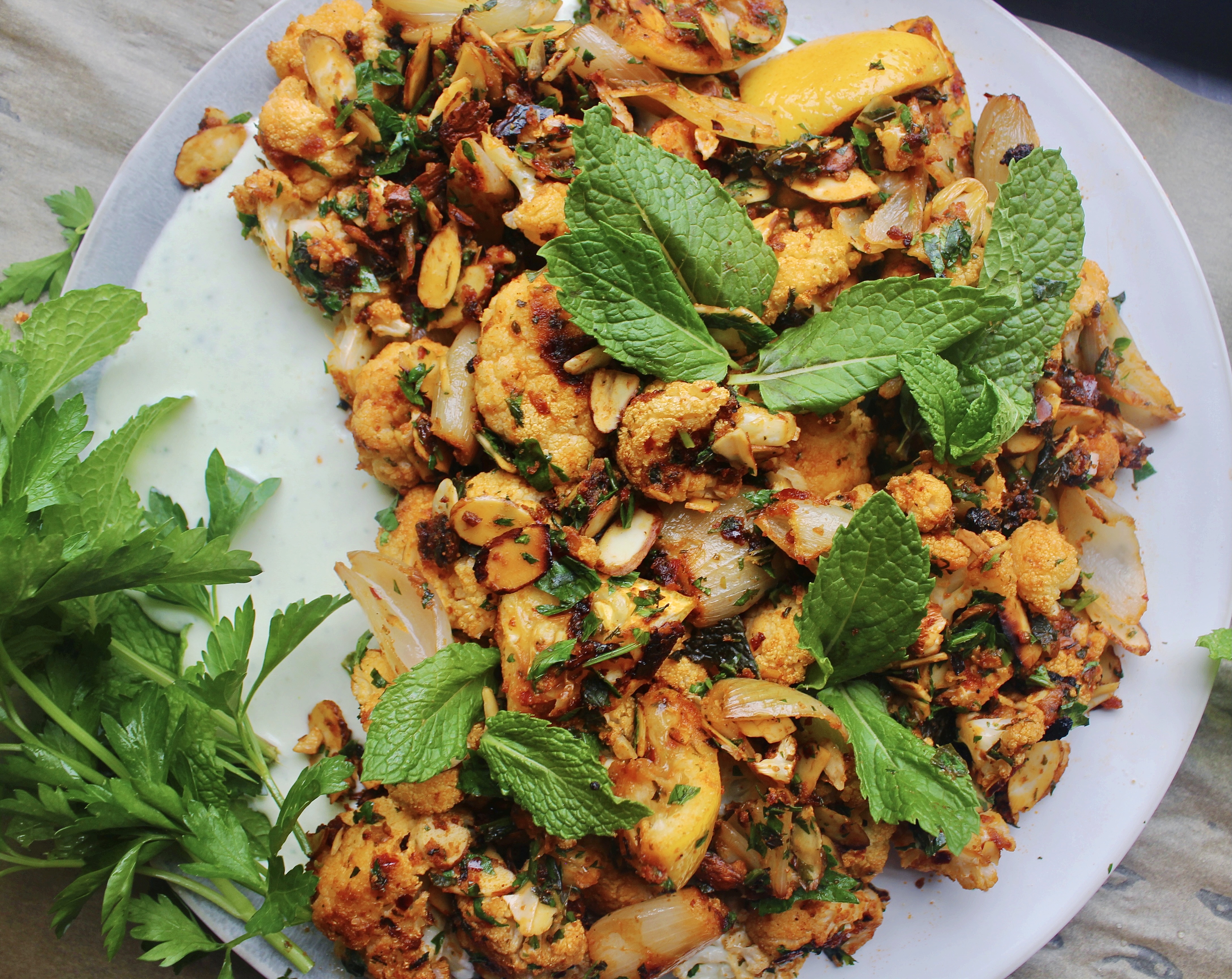 Spicy harissa and a cooling feta yogurt sauce come together in this Harissa Roasted Cauliflower with Toasted Almonds and Feta Yogurt to make the most impressive yet easy side!