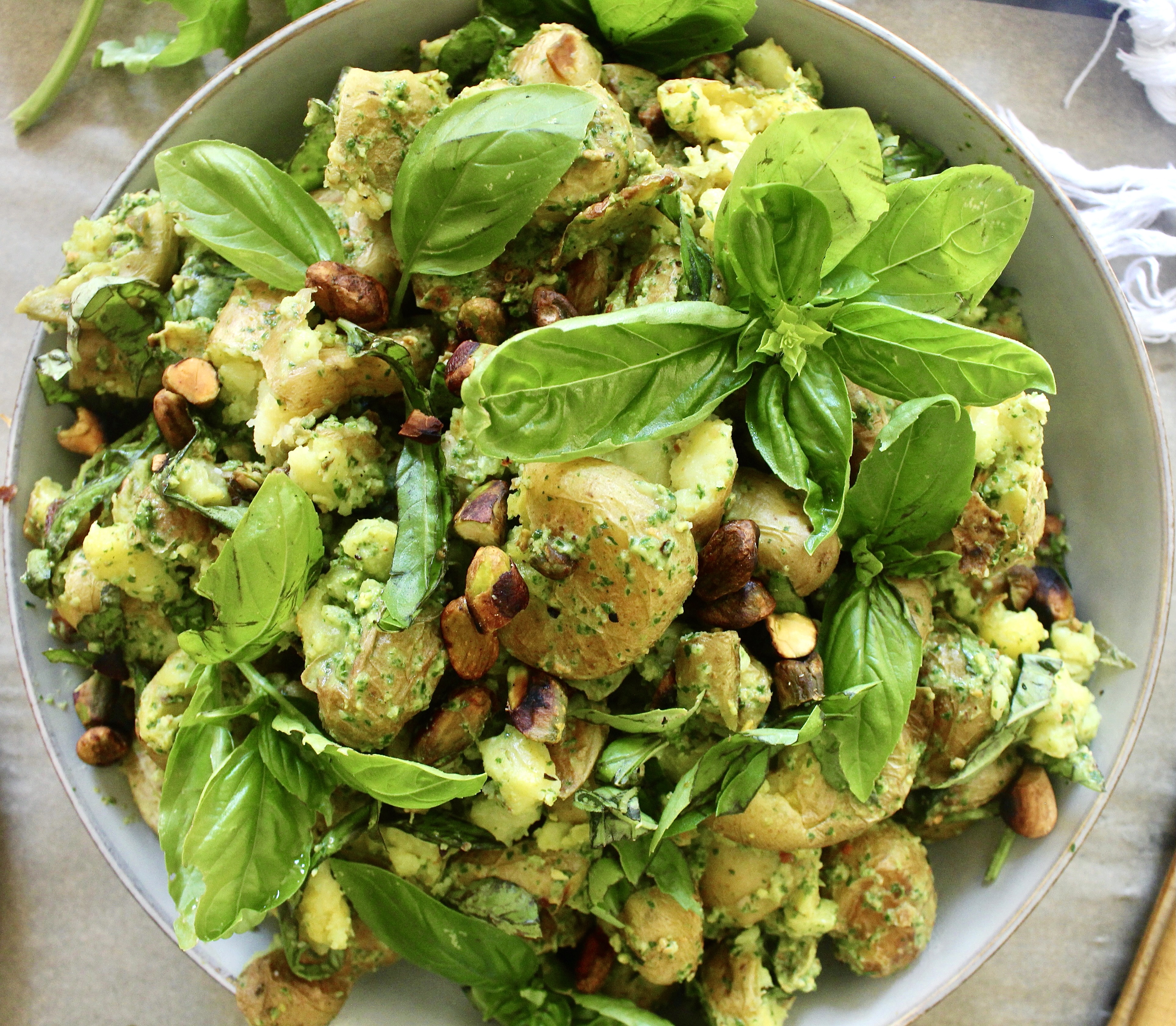 Crispy smashed baby potatoes tossed in a simple arugula pesto: This Smashed Pistachio Pesto di Rucola Potato Salad is the best summer mayo-free potato salad!