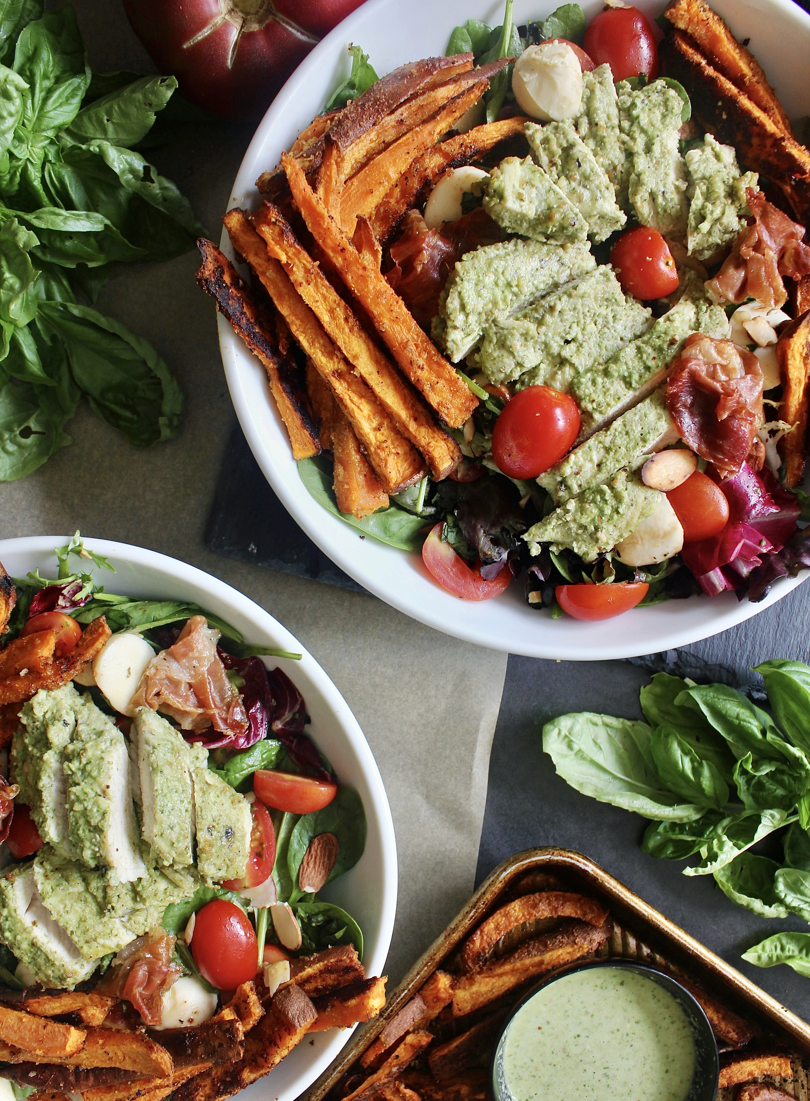 Crispy roasted sweet potato fries and prosciutto baked with juicy pesto chicken and tossed with fresh mozzarella, cherry tomatoes, and simply dressed greens: this Pesto Chicken Sweet Potato Caprese Salad is the ultimate summer salad!