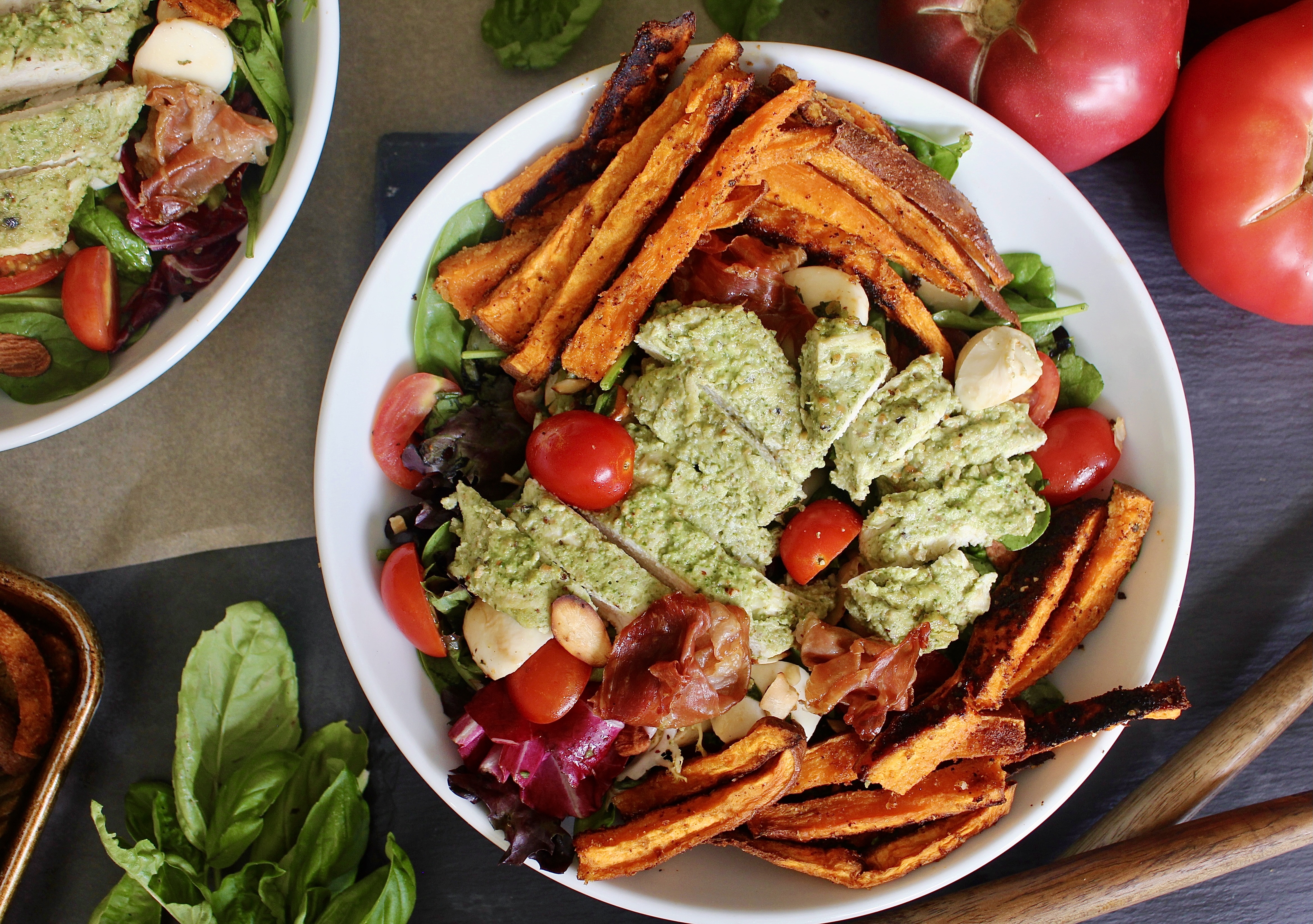 Crispy roasted sweet potato fries and prosciutto baked with juicy pesto chicken and tossed with fresh mozzarella, cherry tomatoes, and simply dressed greens: this Pesto Chicken Sweet Potato Caprese Salad is the ultimate summer salad!