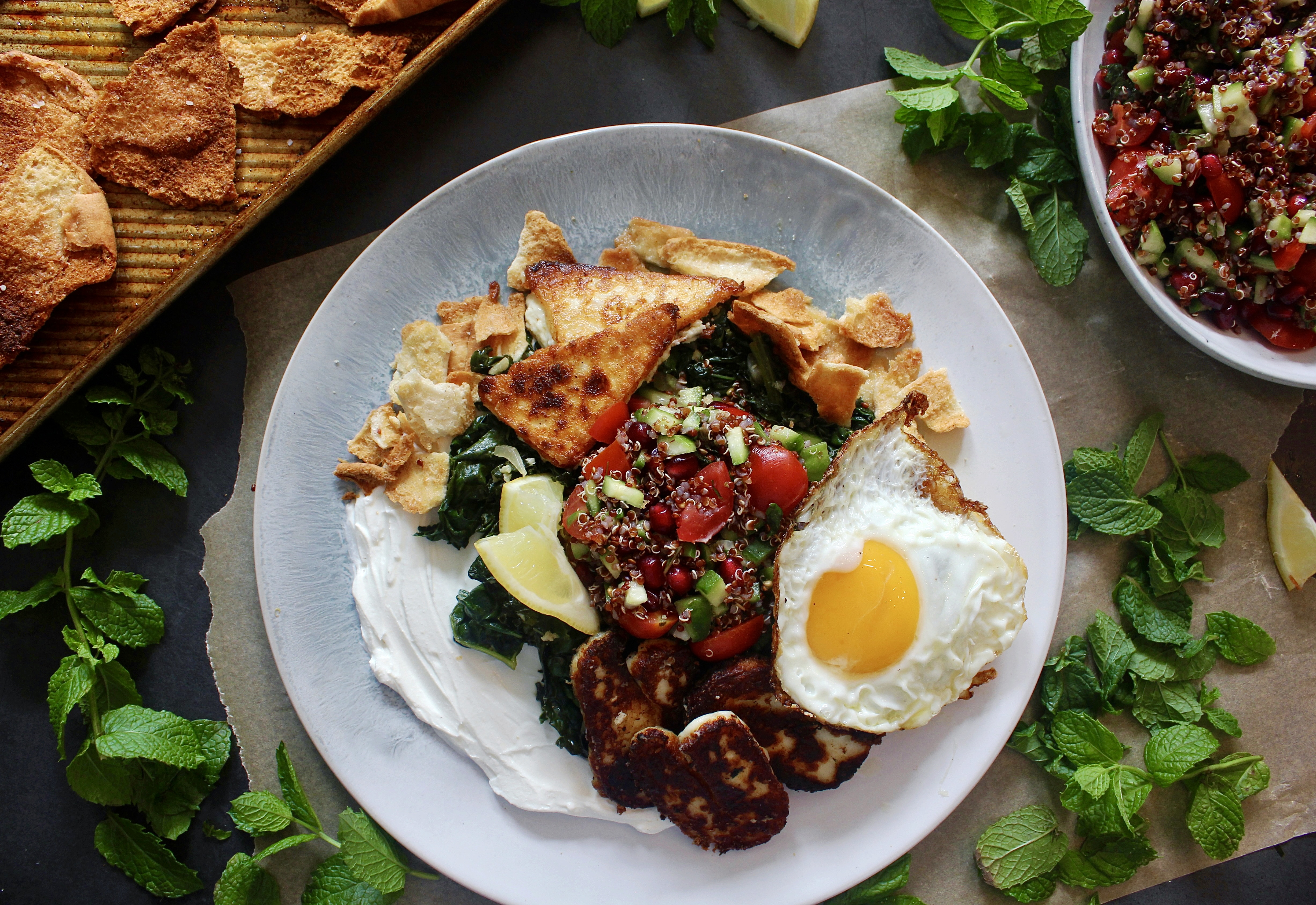 A creamy layer of lemony labneh, white wine garlicky wilted kale, and a few spoonfuls of a pomegranate quinoa salad all finished off with crispy cheese and a fried egg: these Loaded Lebanese Kale, Quinoa Salad, and Fried Egg Plates are seriously next-level amazing.