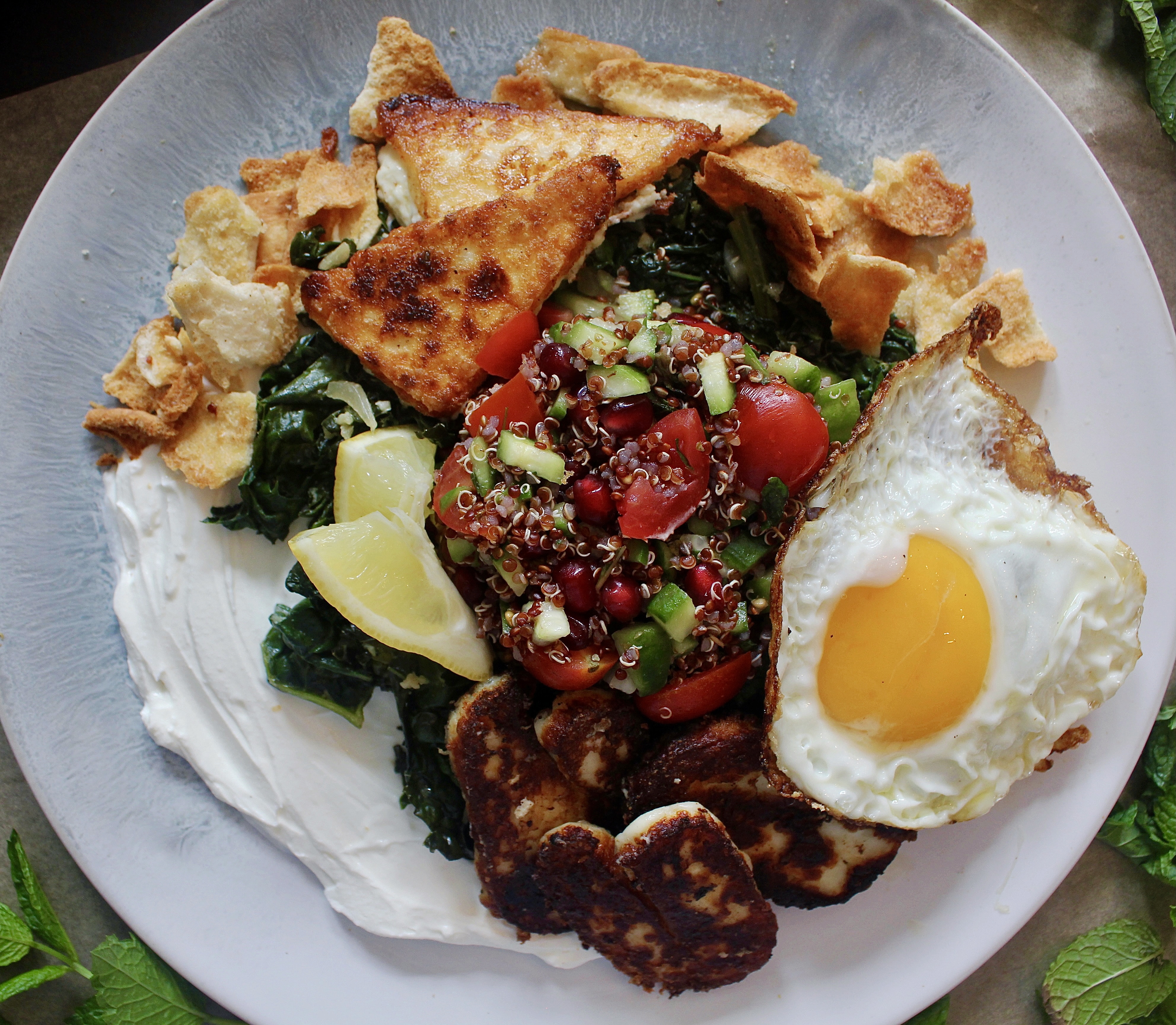 A creamy layer of lemony labneh, white wine garlicky wilted kale, and a few spoonfuls of a pomegranate quinoa salad all finished off with crispy cheese and a fried egg: these Loaded Lebanese Kale, Quinoa Salad, and Fried Egg Plates are seriously next-level amazing.