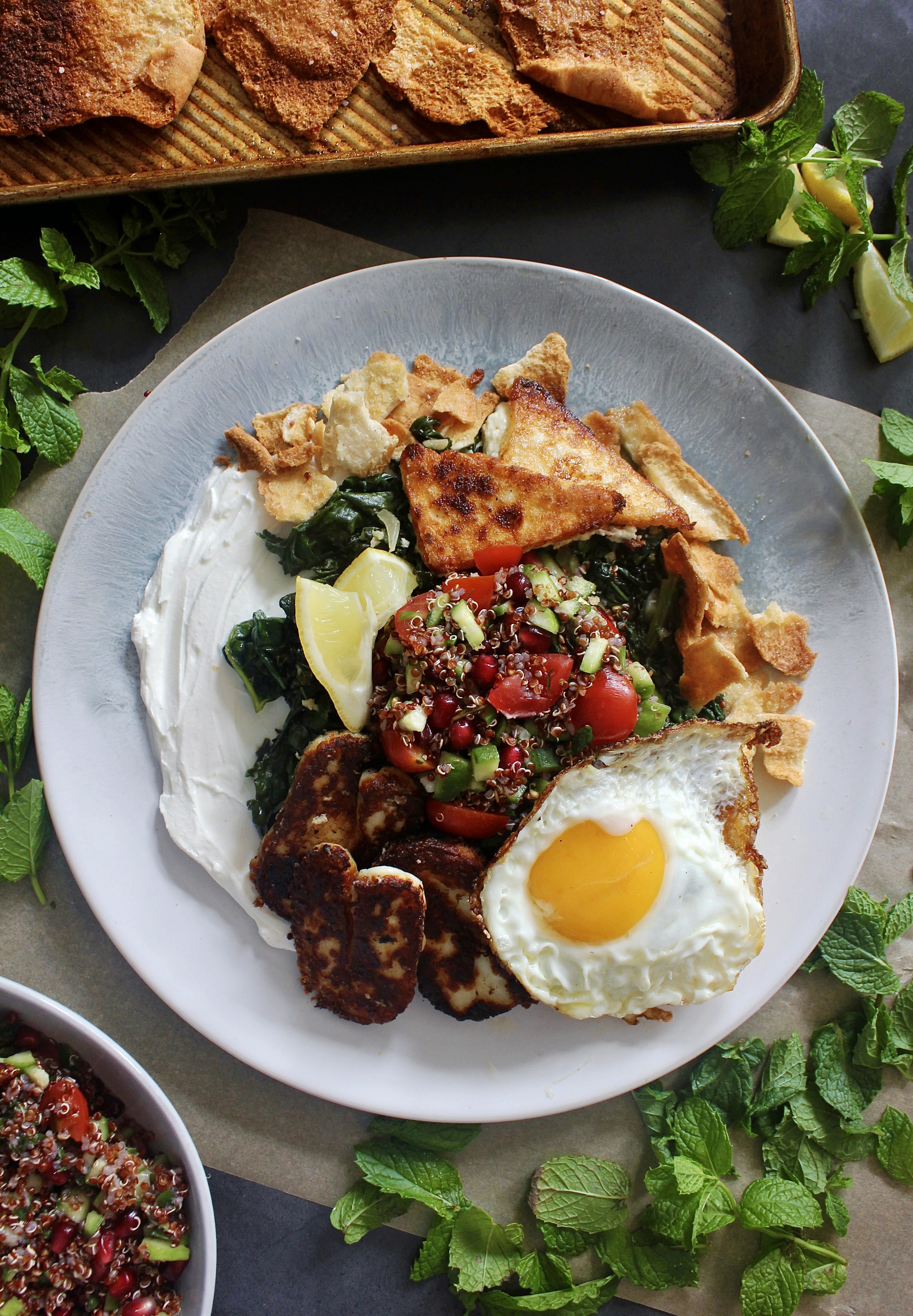 A creamy layer of lemony labneh, white wine garlicky wilted kale, and a few spoonfuls of a pomegranate quinoa salad all finished off with crispy cheese and a fried egg: these Loaded Lebanese Kale, Quinoa Salad, and Fried Egg Plates are seriously next-level amazing.