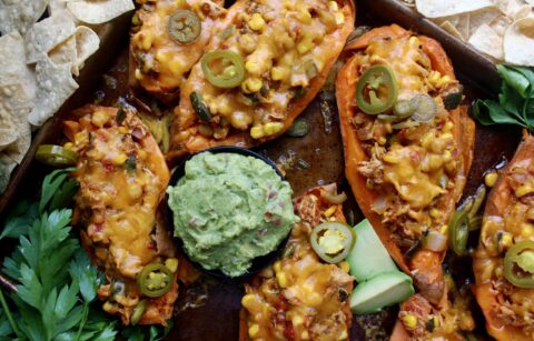 Juicy shredded chicken cooked down with seasoned corn, beans, peppers, and tomatoes all stuffed into a crispy sweet potato skin with tons of cheese: these Mexican Cheddar Stuffed Sweet Potato Skins are the ultimate fiesta food.