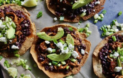 With juicy, spiced pulled chicken and tons of fresh flavors layered over a homemade crispy pita shell: these Chicken, Bean, Avocado, and Feta Pita Tostadas are the messy goodness that we all need right now!