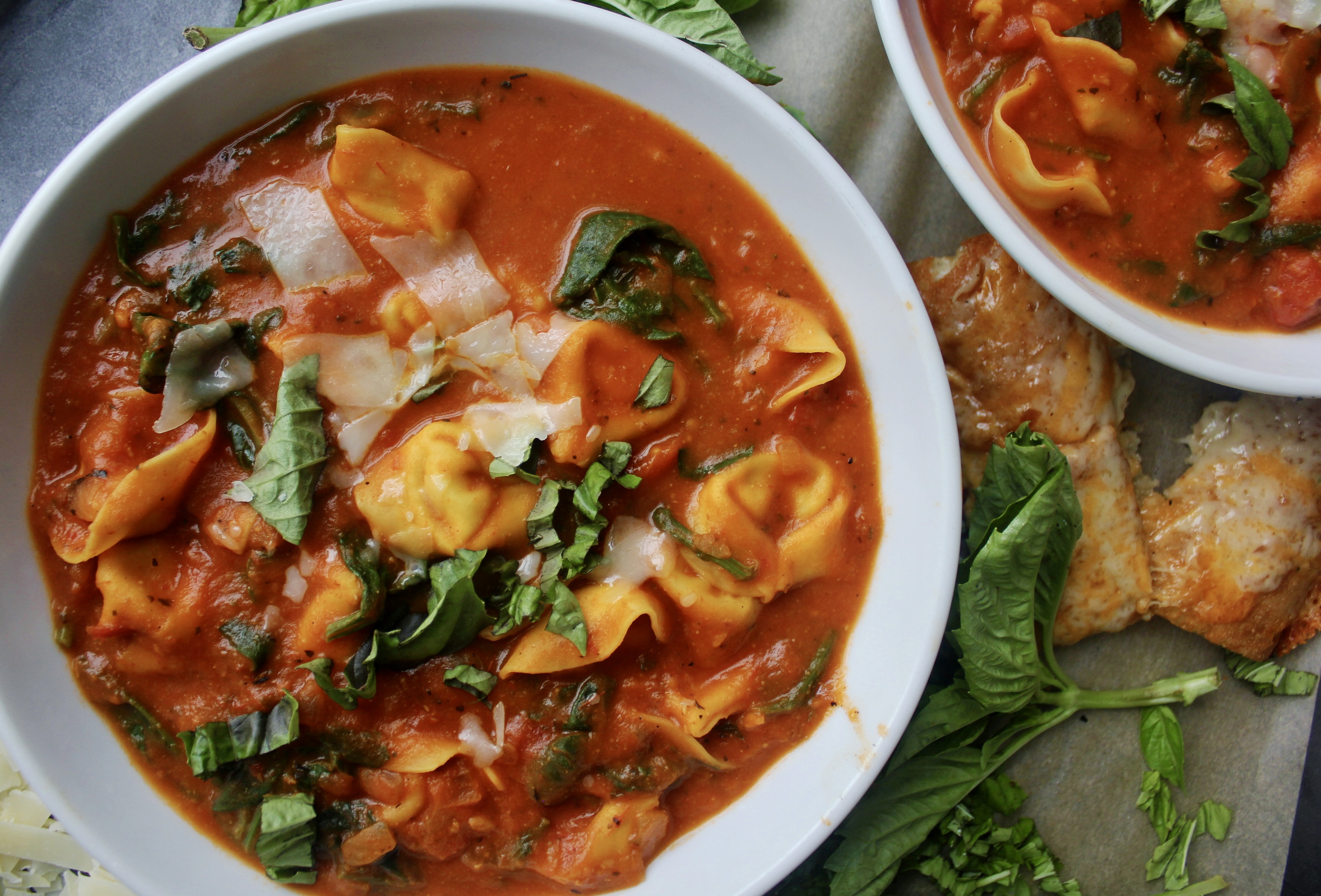 Cheese tortellini tossed into a cozy, hearty bowl of homemade tomato soup with tons of parmesan and fresh spinach: this Lightened Up Creamy Tomato and Tortellini Soup makes for the best warming dinner.