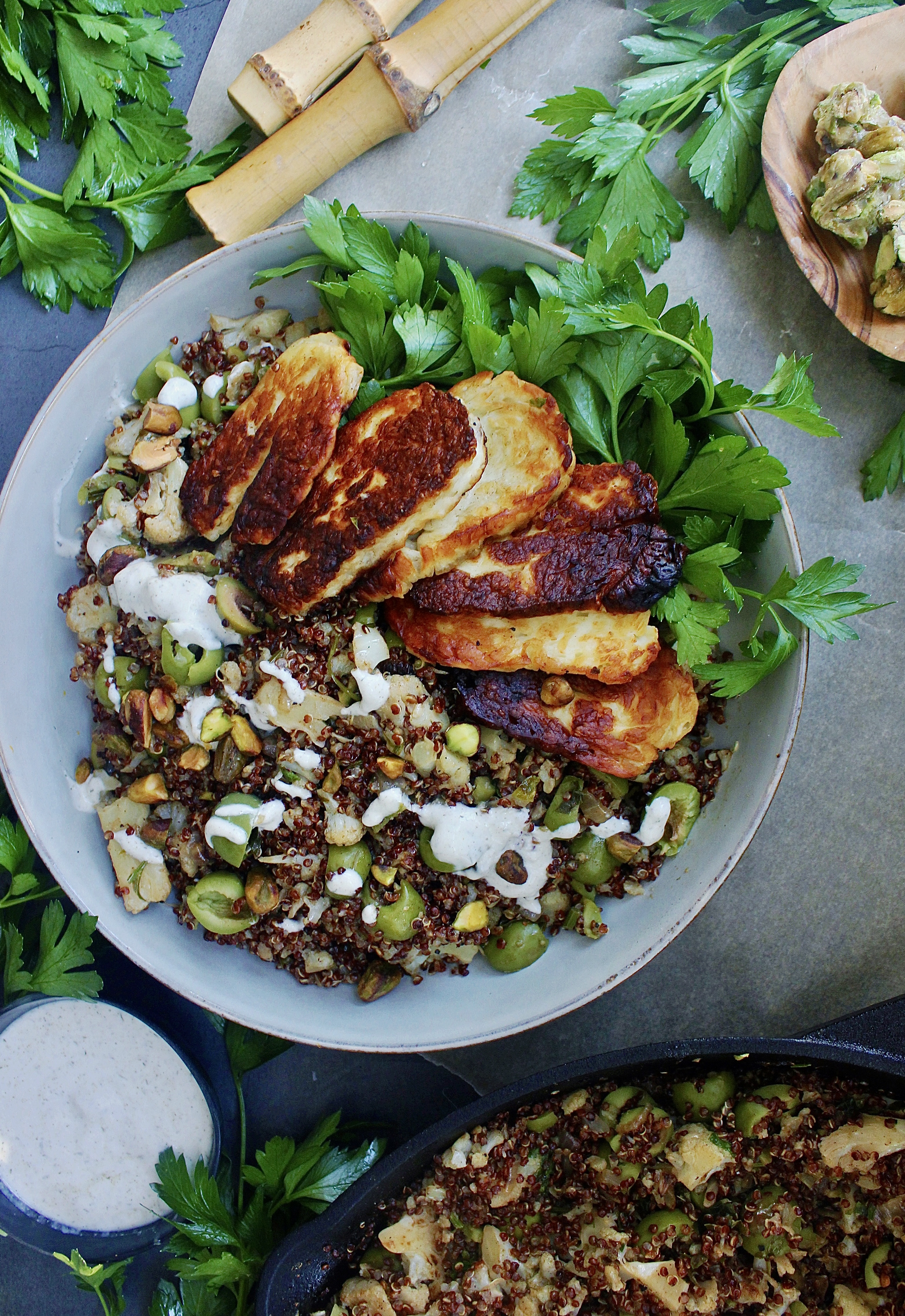 Caramelized garlic onion and cauliflower toss up with an olive and herbed quinoa finished off with some pan fried halloumi cheese and a greek yogurt drizzle: these Charred Halloumi Mediterranean Red Quinoa Bowls are the most epic meatless dinner!