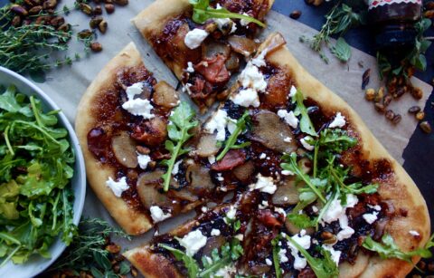 A warm, fluffy oven baked pizza layered with a jammy balsamic fig spread, honey caramelized pears, salty prosciutto, and melty goat cheese all topped off with a pistachio arugula salad: this Balsamic Caramelized Pear, Fig, and Prosciutto Pizza could not get any better.