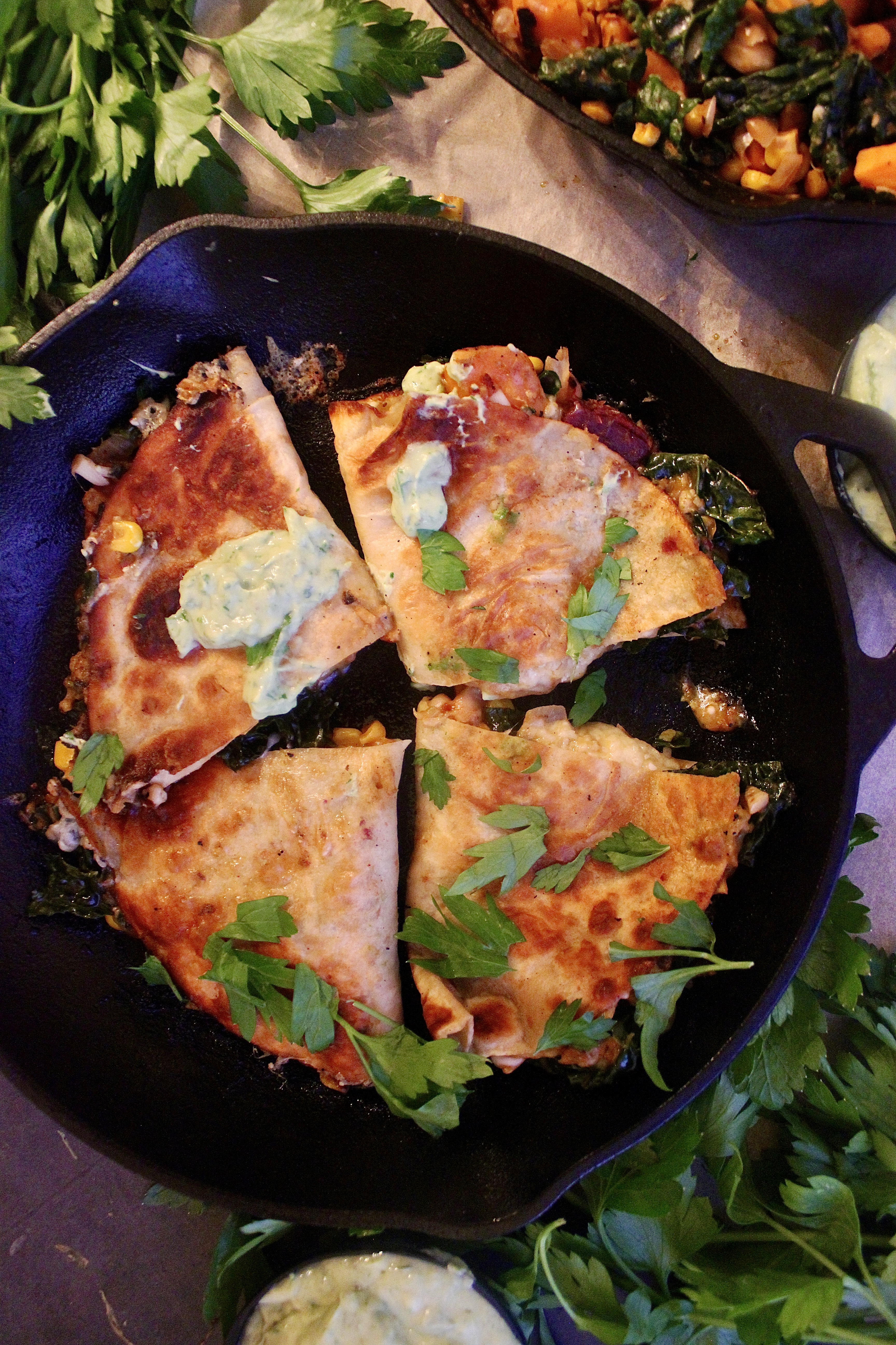 Perfectly seasoned, caramelized sweet potatoes cooked down with corn, white beans, and kale stuffed into a cheesy, toasty tortilla and dipped into a creamy avocado crema: these Sweet Potato White Bean Chili Quesadillas are my favorite easy dinner.