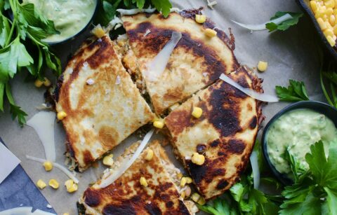 Perfectly seasoned, caramelized sweet potatoes cooked down with corn, white beans, and kale stuffed into a cheesy, toasty tortilla and dipped into a creamy avocado crema: these Sweet Potato White Bean Chili Quesadillas are my favorite easy dinner.