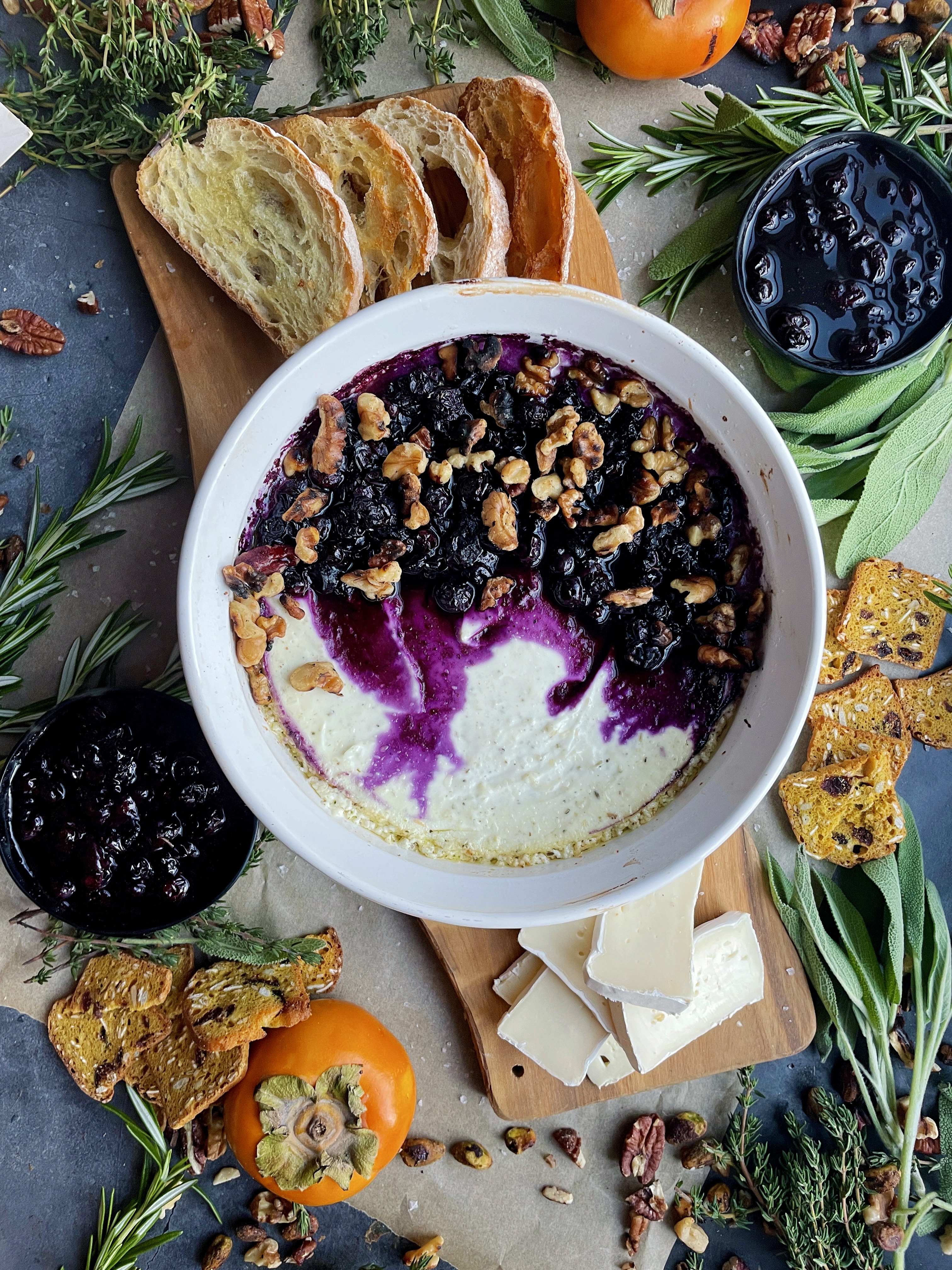 A creamy, tangy whipped three cheese base baked with jammy blueberries all topped off with toasty walnuts and a slice of crusty bread: this Baked Blueberry Walnut Goat Cheese Dip is the ultimate party appetizer!