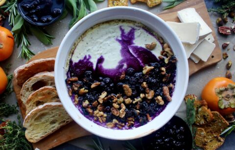 A creamy, tangy whipped three cheese base baked with jammy blueberries all topped off with toasty walnuts and a slice of crusty bread: this Baked Blueberry Walnut Goat Cheese Dip is the ultimate party appetizer!