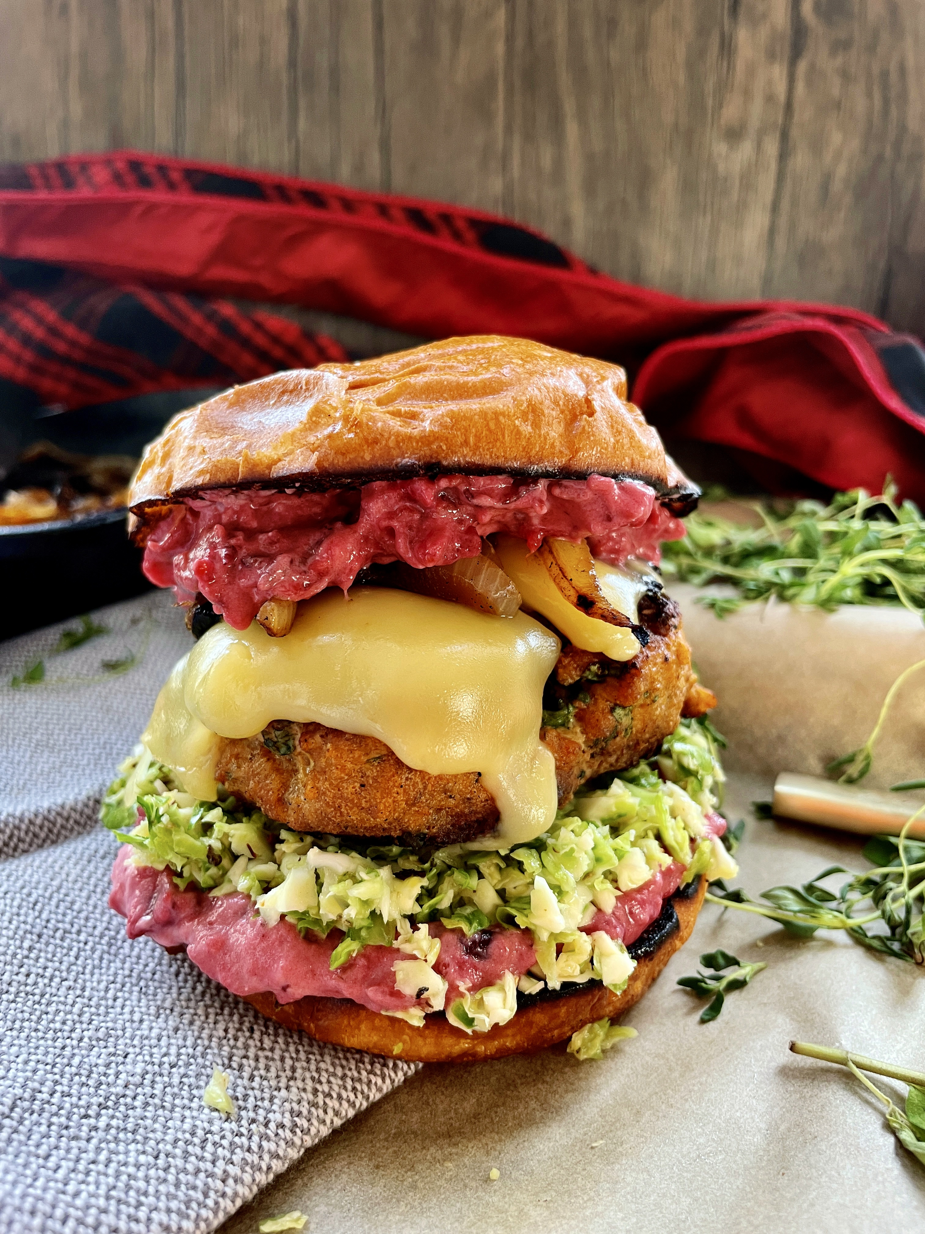 A creamy, tangy pancetta cranberry remoulade spread on a crispy pretzel bun with a brussels sprouts slaw, caramelized onions, and a melty juicy gouda turkey burger: these Cranberry Gouda Turkey Burgers with Caramelized Onions are the ultimate Christmas burger!!