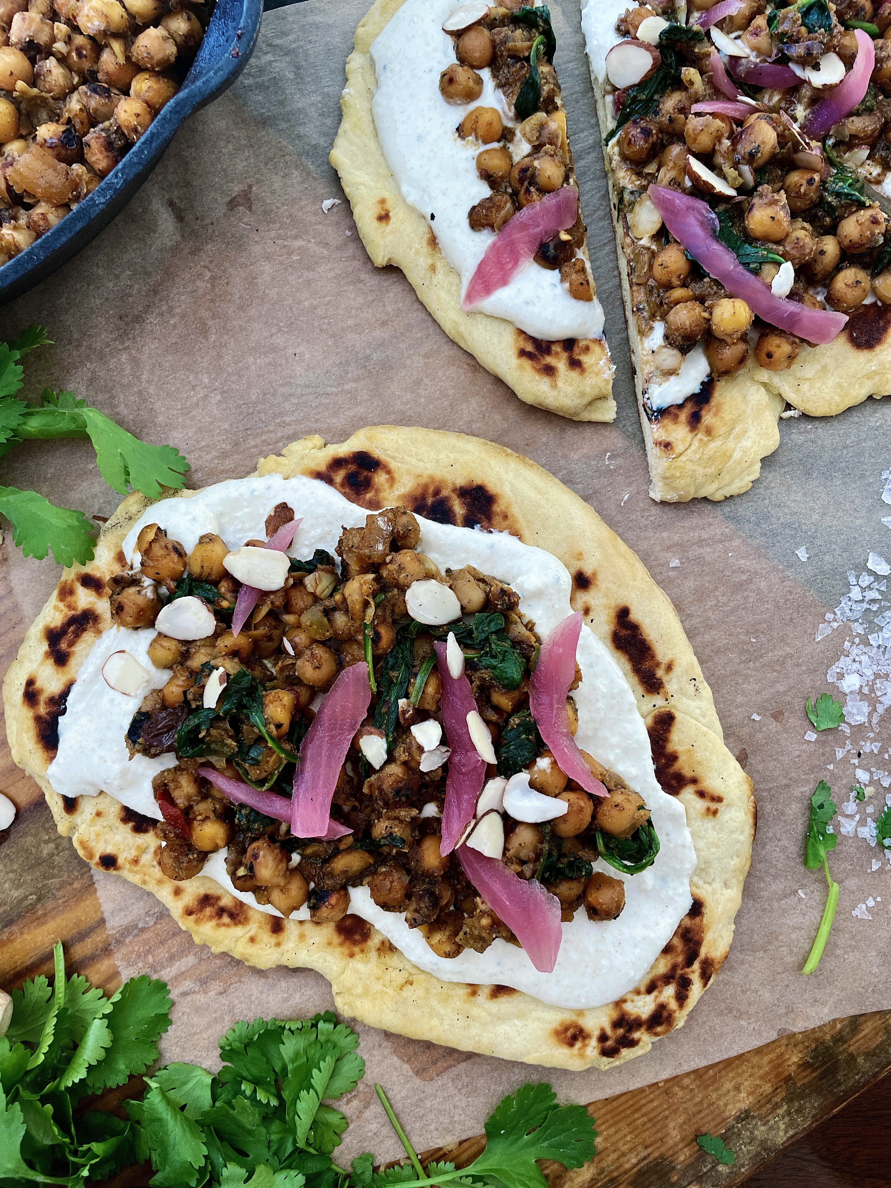  Crispy, crunchy chickpeas toasted in mango chutney and all the good Indian spices wilted down with some garlicky spinach and served over a layer of a salty fresh yogurt sauce and warm naan: these Indian Chickpea Naan Flatbreads with Cucumber Feta Crema are truly a bite of heaven.  