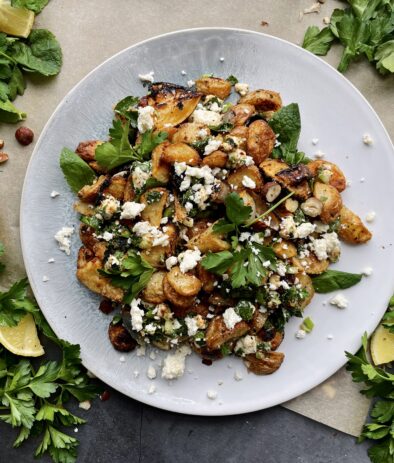 Roasted lemon, caramelized shallots, and your favorite hummus roasted up with baby potatoes and topped with allll the herbs and feta: these Crispy Greek Hummus Crusted Potatoes are an all time fav side!