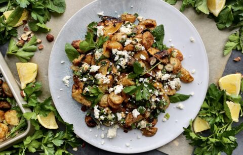 Roasted lemon, caramelized shallots, and your favorite hummus roasted up with baby potatoes and topped with allll the herbs and feta: these Crispy Greek Hummus Crusted Potatoes are an all time fav side!
