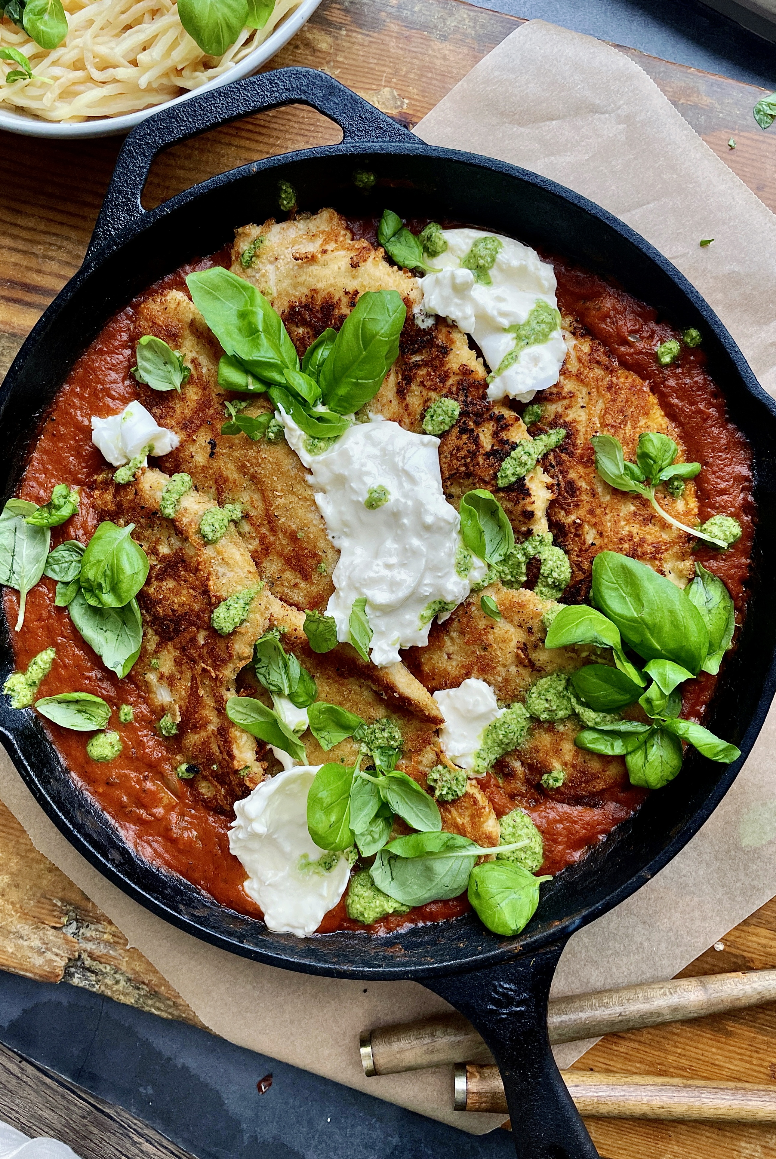 Crispy, lightly seared chicken breasts tucked into a lightened up vodka sauce all finished off in the oven and topped with creamy burrata and pesto: this Skillet Vodka Sauce Chicken Parmesan with Burrata is truly a death row meal. 