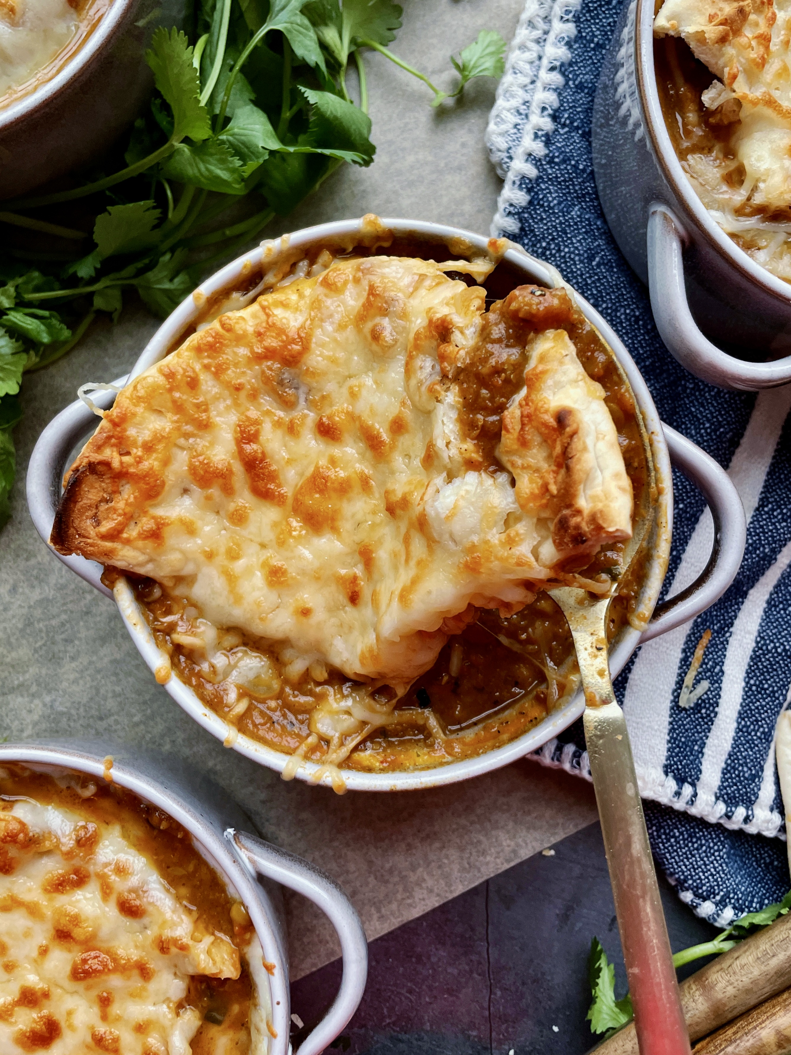 The most creamy, spiced curried lentil soup simmered with alllll the flavors on the stove and divided into “French onion soup” style ramekins with melty fontina and plush naan: this Cheesy Curried Lentil Soup Ramekins with Naan Croutons recipe is the best way to warm up this winter!