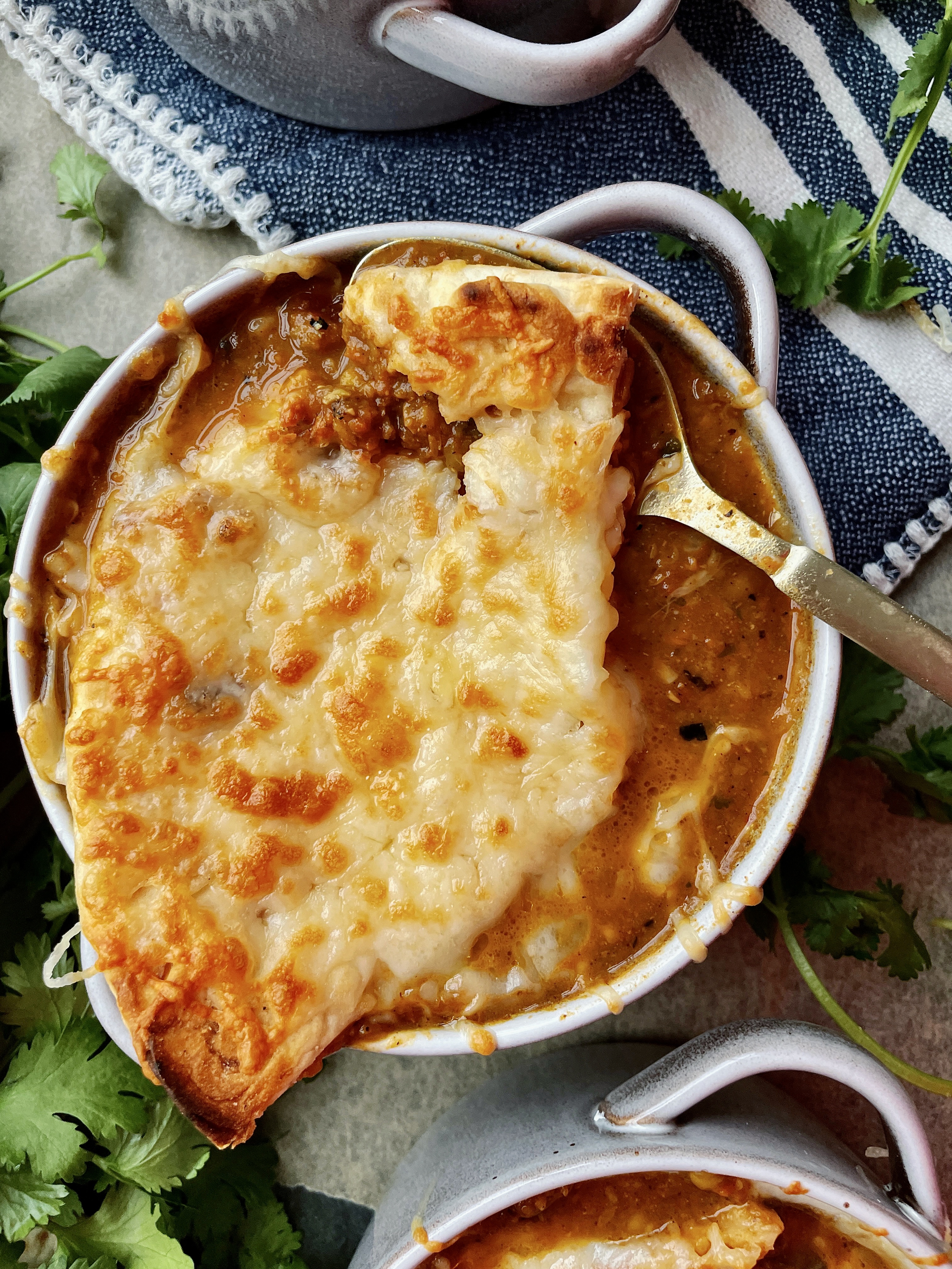 The most creamy, spiced curried lentil soup simmered with alllll the flavors on the stove and divided into “French onion soup” style ramekins with melty fontina and plush naan: this Cheesy Curried Lentil Soup Ramekins with Naan Croutons recipe is the best way to warm up this winter!