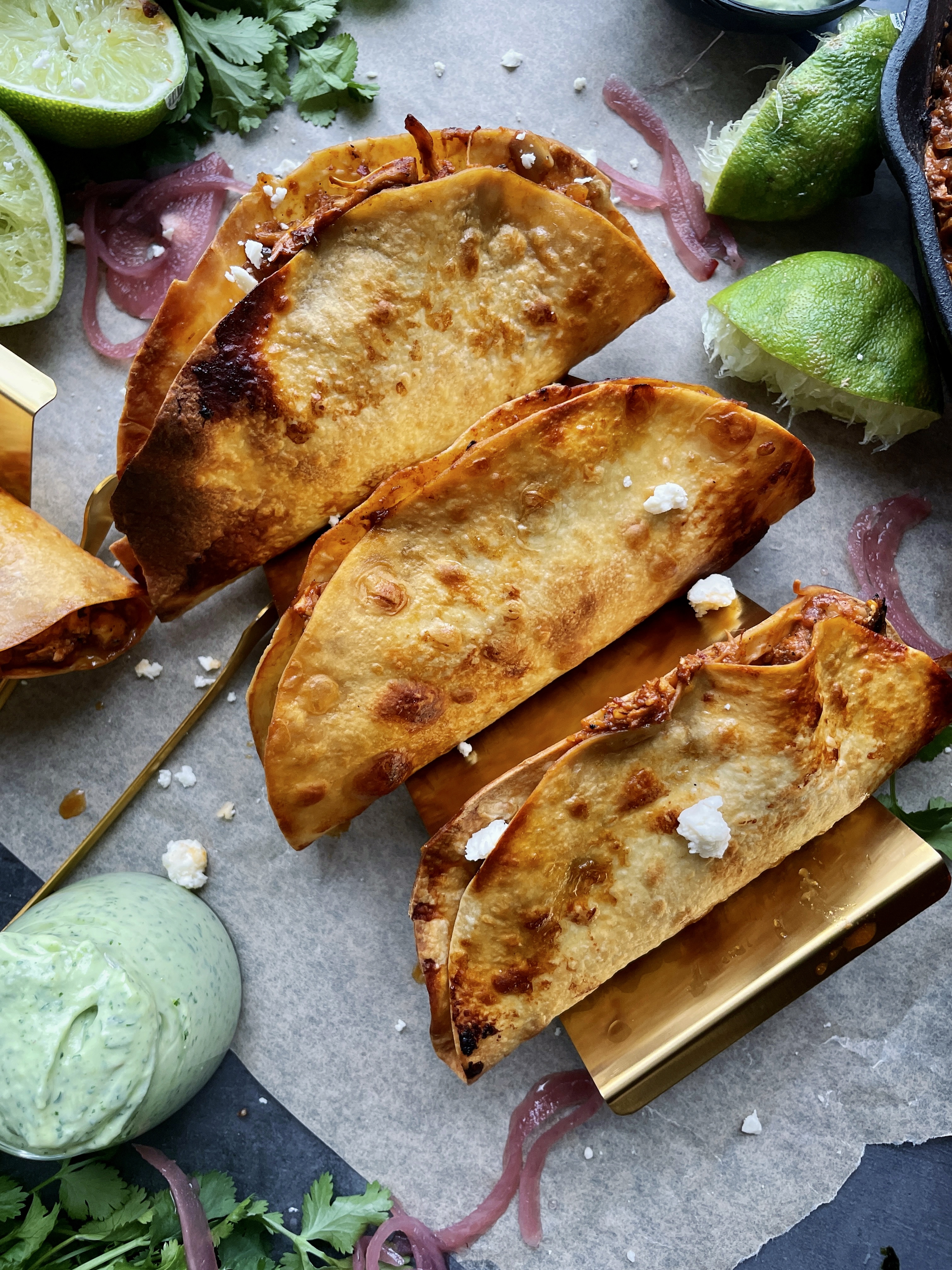 Homemade, golden crispy taco shells stuffed with adobo pulled chicken and jackfruit baked to perfection with all the melty cheese and dipped in a cooling avocado cilantro sauce: these Crispy Chicken and Jackfruit Tinga Tacos with Avocado Crema are truly a heavenly bite.