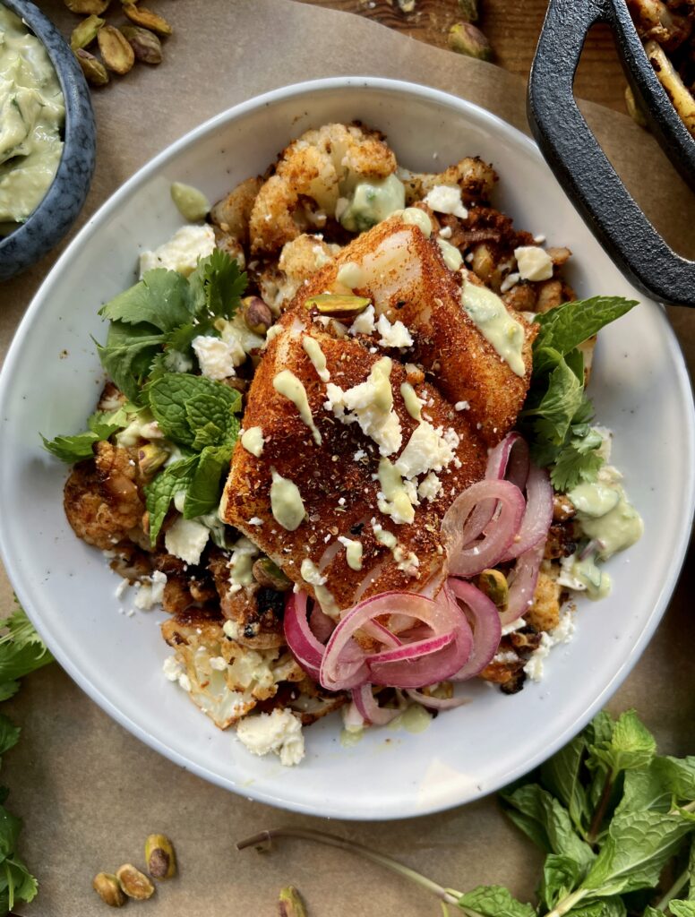 Crispy seared and roasted cauliflower florets tossed up in the most flavorful spice blend topped with flaky fish and a crunchy creamy avocado walnut herb blend: these Avocado Chimichurri Fish Taco Cauliflower Bowls truly are a burst of flavor!