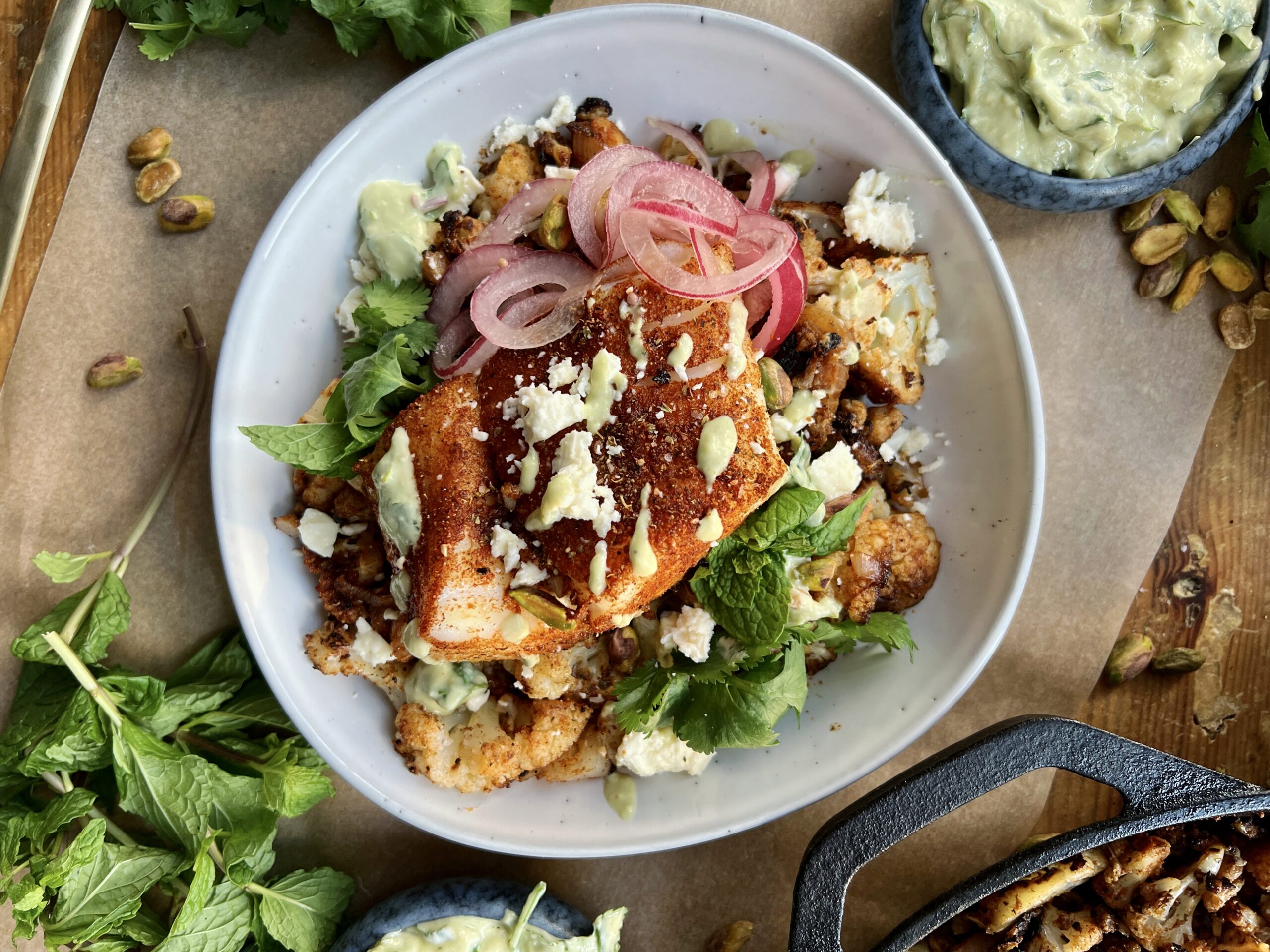 Crispy seared and roasted cauliflower florets tossed up in the most flavorful spice blend topped with flaky fish and a crunchy creamy avocado walnut herb blend: these Avocado Chimichurri Fish Taco Cauliflower Bowls truly are a burst of flavor!