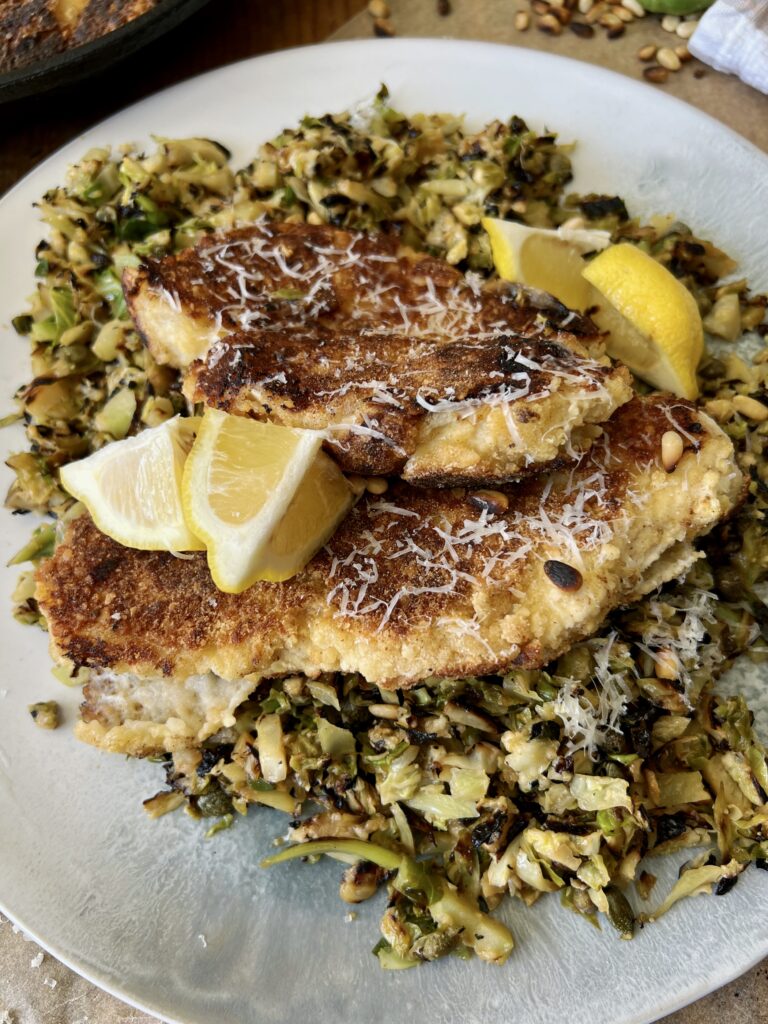 Juicy marinated, golden seared chicken on a simple parmesan briney brussels hash: this Crispy Chicken Over Lemon Caper Brussels is a burst of flavor!